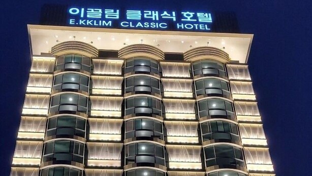 Un hotel de varias plantas con un diseño moderno, que cuenta con una serie de balcones y ventanas iluminadas.