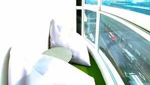 Una habitación con un ventanal grande, una cama y vistas a una calle concurrida.