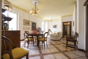 Zona pranzo con lampadario, sedie in legno, tavolo rotondo e divano.