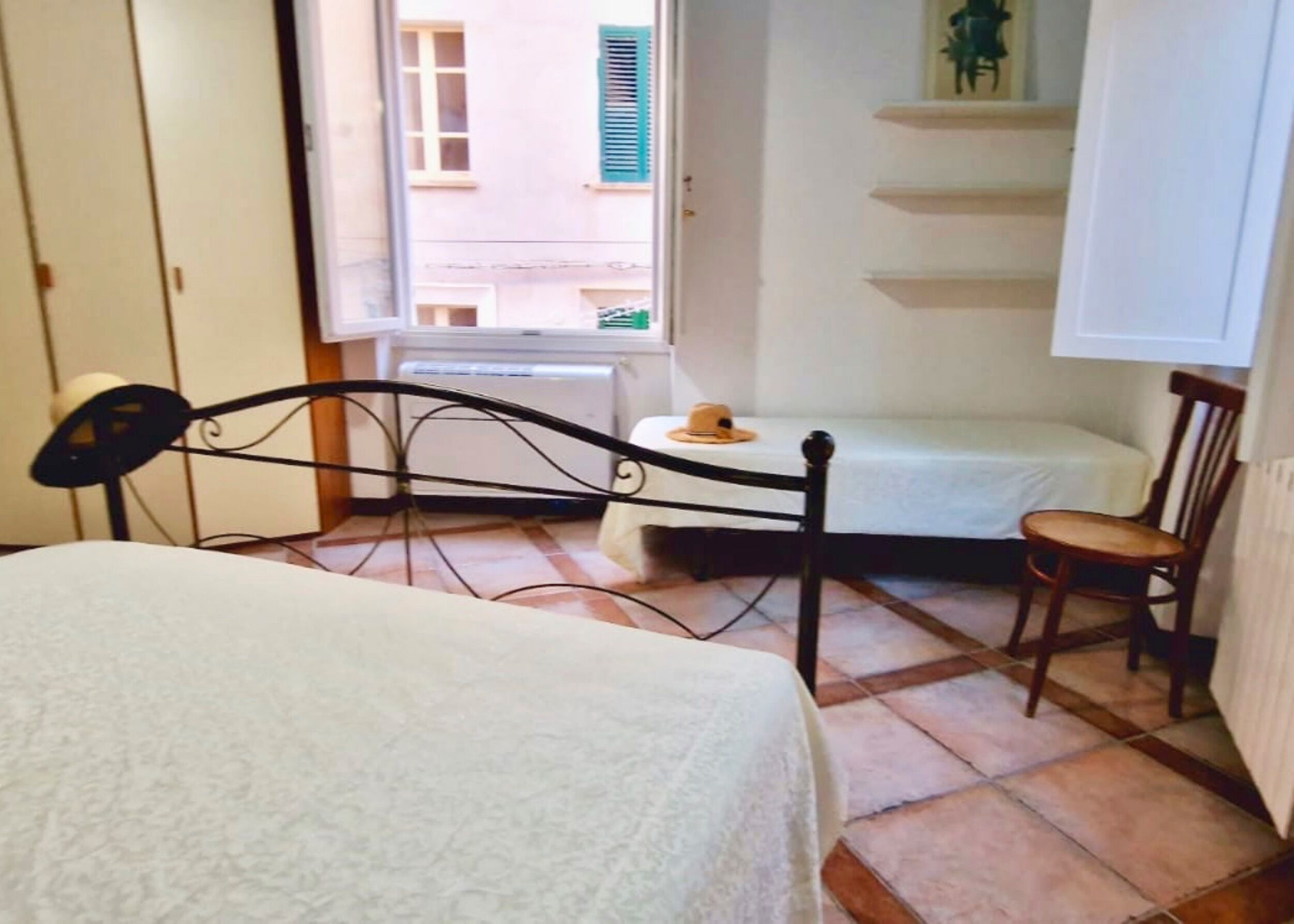 Una stanza piccola e accogliente con un letto, una sedia, un tavolo e una finestra vista edifici.