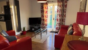 Una sala de estar moderna con sofás rojos, una mesa de centro de madera y un televisor.