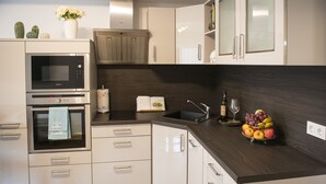 Uma cozinha moderna com eletrodomésticos embutidos, bancada de madeira e uma fruteira.