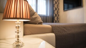 Quarto de hotel moderno, com vista clara para a cama, uma luminária de cabeceira e uma janela com cortinas.