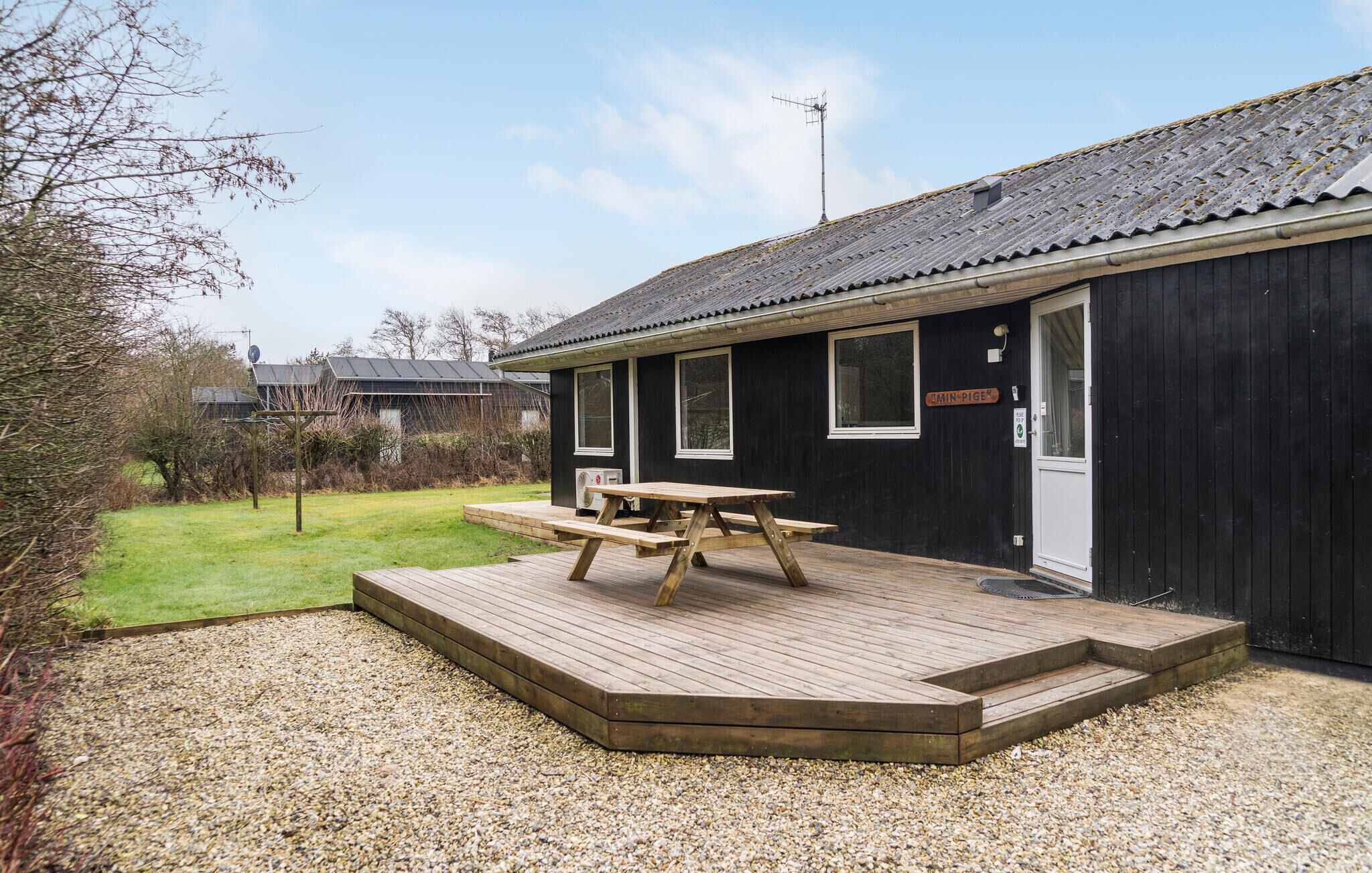 A wooden building with a picnic table on a gravel deck.