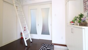 Un pasillo con una escalera blanca, puertas de vidrio esmerilado, un cartel de bienvenida y una planta en maceta.