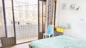 A bedroom with a bed, a desk, a chair, and a view of a construction site through a window. - XIAN BnB (Jinhu)