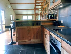 Une cuisine moderne avec des meubles en bois, un plan de travail noir et une cuisinière encastrée.