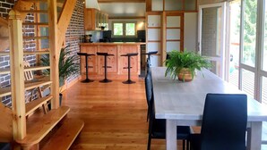 A modern kitchen with wooden accents, a central island, and a staircase leading to an upper level.