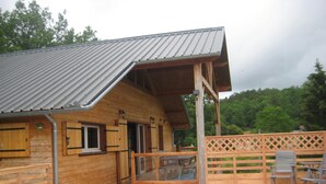 A wooden cabin with a metal roof, a glass door entrance, and a pool area.