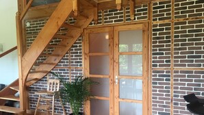 A wooden staircase leading to a room with a brick wall and a sliding glass door.