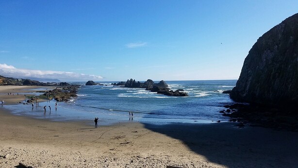 Una playa con formaciones rocosas y cielos despejados.