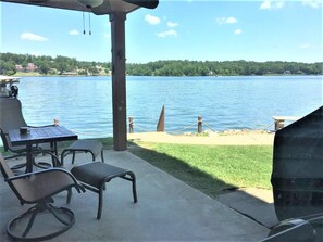 Un patio cubierto con vistas a un lago, una parrilla y mobiliario de exterior.