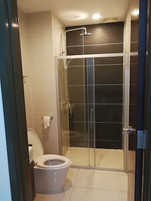 Et moderne badeværelse med en brusekabine i glas, toilet og et håndklædetørrestativ.