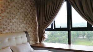 A bedroom with a large bed, a headboard, a window with curtains, and a wall with a geometric pattern.