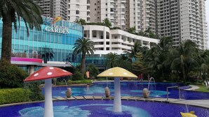 A modern hotel with a pool area featuring mushroom-shaped water features and a large building with a sign reading "COUNTRY GARDEN" in the background.