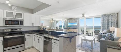 A modern kitchen with built-in appliances, a dining area with a view, and a balcony with outdoor furniture.