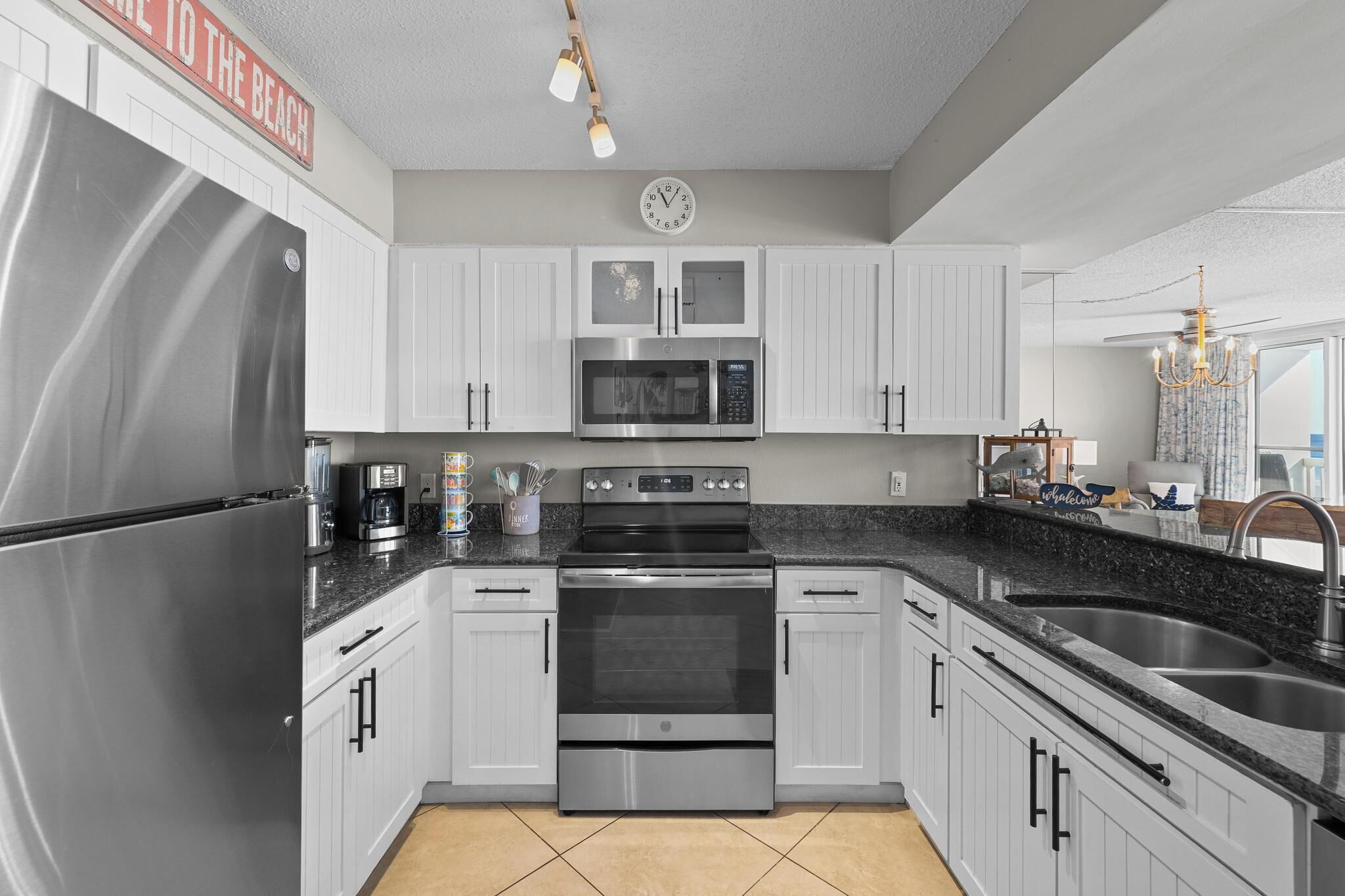 A modern kitchen with stainless steel appliances, white cabinetry, and a granite countertop.