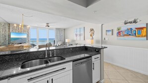 Una cucina moderna con piani di lavoro in granito, elettrodomestici in acciaio inossidabile e vista all'esterno.
