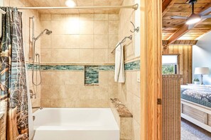 A bathroom with a bathtub, shower, and tiled walls.