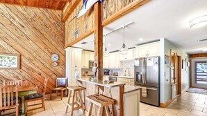 Una cocina con detalles de madera, una zona de bar y un comedor.
