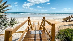 Un muelle de madera que conduce a una playa con vistas al océano.