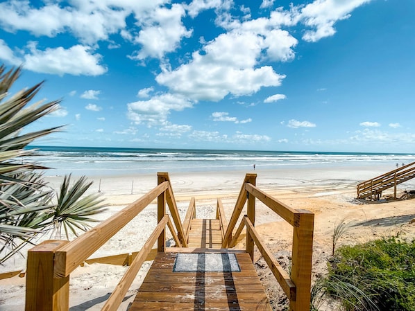 A wooden boardwalk leading to a beach with ocean views.