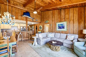 A wooden interior with a dining area, kitchen, and living room with a sofa and coffee table.