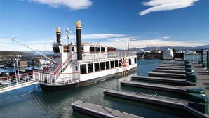 Un bateau fluvial était amarré dans une marina dotée de plusieurs quais, le ciel était dégagé et des montagnes se dressaient à l’horizon.