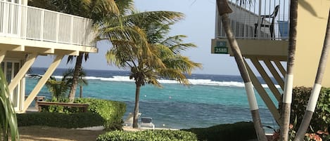 A beachfront property with a balcony overlooking the ocean, a well-maintained lawn, and a clear view of the sea.
