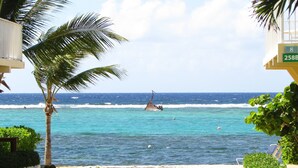 Uitzicht op een strand met een palmboom, golven en een rederspost.