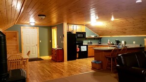 A cozy, wood-paneled kitchen with a dining area, featuring a refrigerator, microwave, and coffee maker.