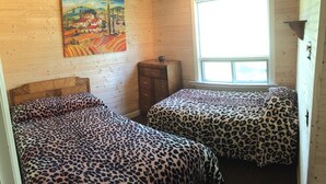 A room with two beds, a wooden dresser, a painting on the wall, and a window. - GRINDSTONE PARK, minutes from water & Beach. Hunting and fishing Largest MOOSE (Riverton)