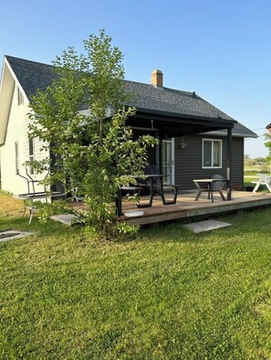 Ein zweistöckiges Haus mit einer Terrasse, einem Schornstein und einem Baum im Vorgarten.
