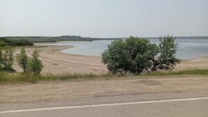 Una carretera serpentea junto a un río con una playa arenosa y vegetación escasa.