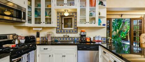 A kitchen with white cabinets, a black stove, a dishwasher, and a tiled backsplash.