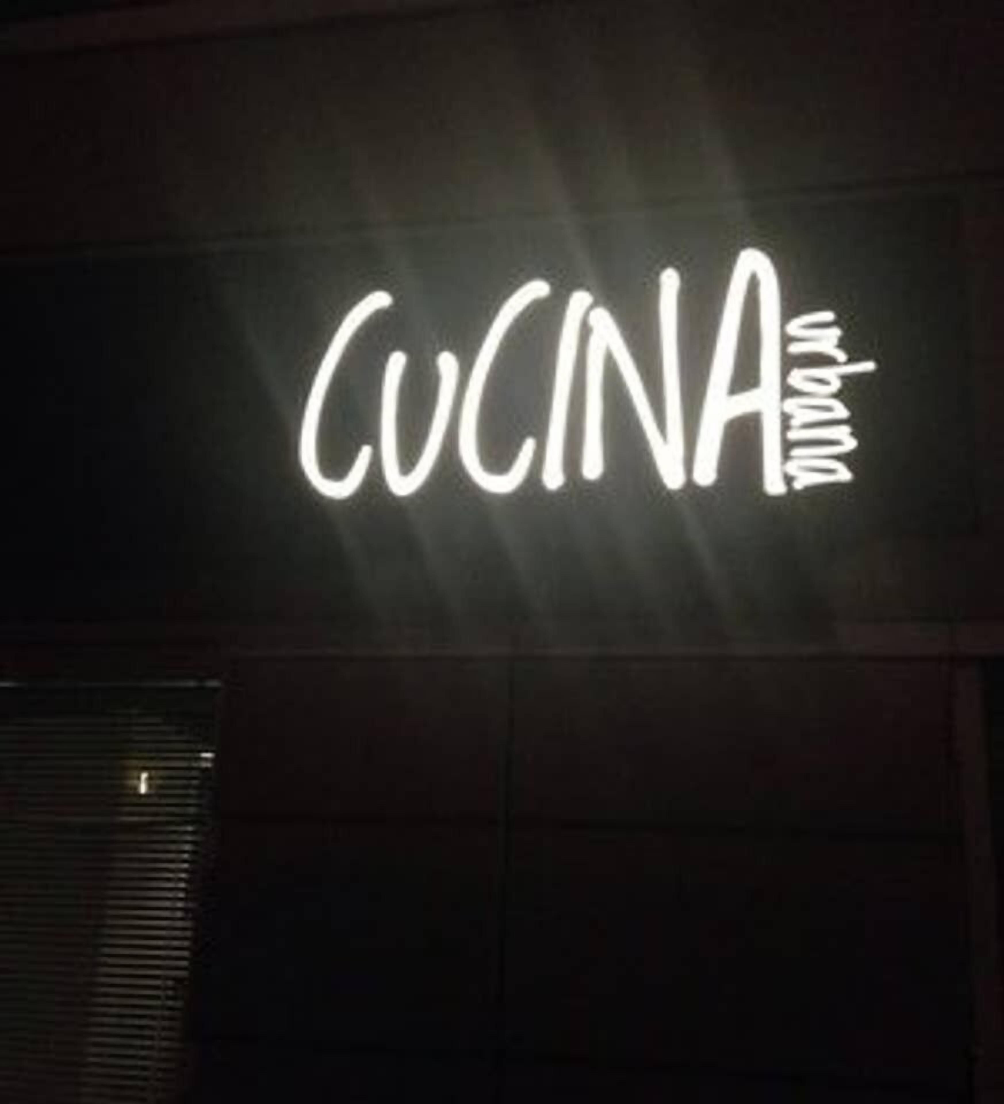 A sign with the word "CUCINA" illuminated in white on a dark background.