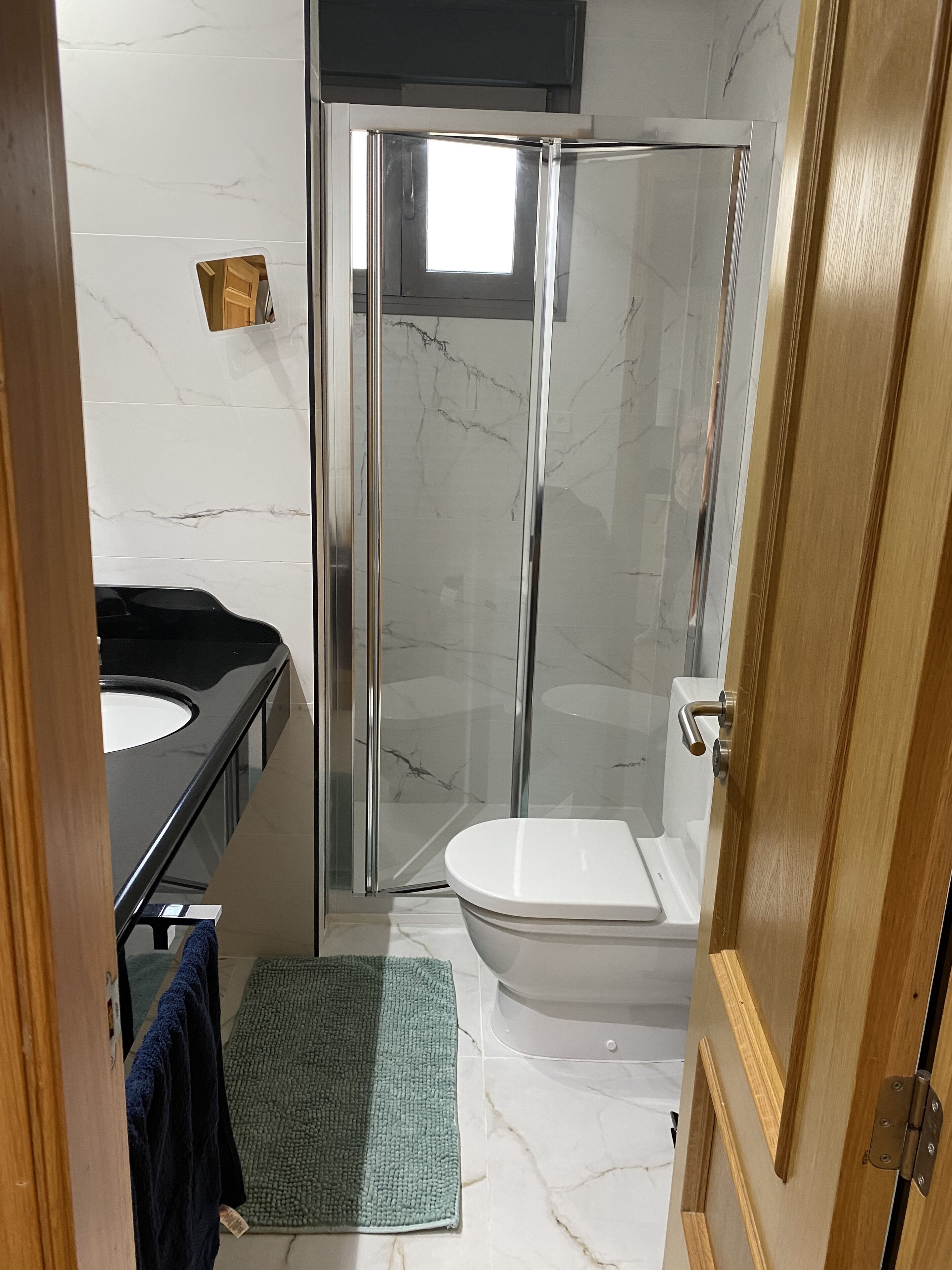 Ein Badezimmer mit einer Duschkabine, einer weißen Toilette und einem schwarzen Waschbecken.