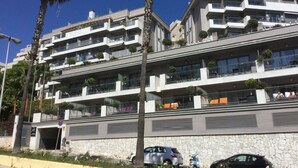 Ein mehrstöckiges Hotel mit Balkonen, einer Stein-Fassade und abgestellten Autos.