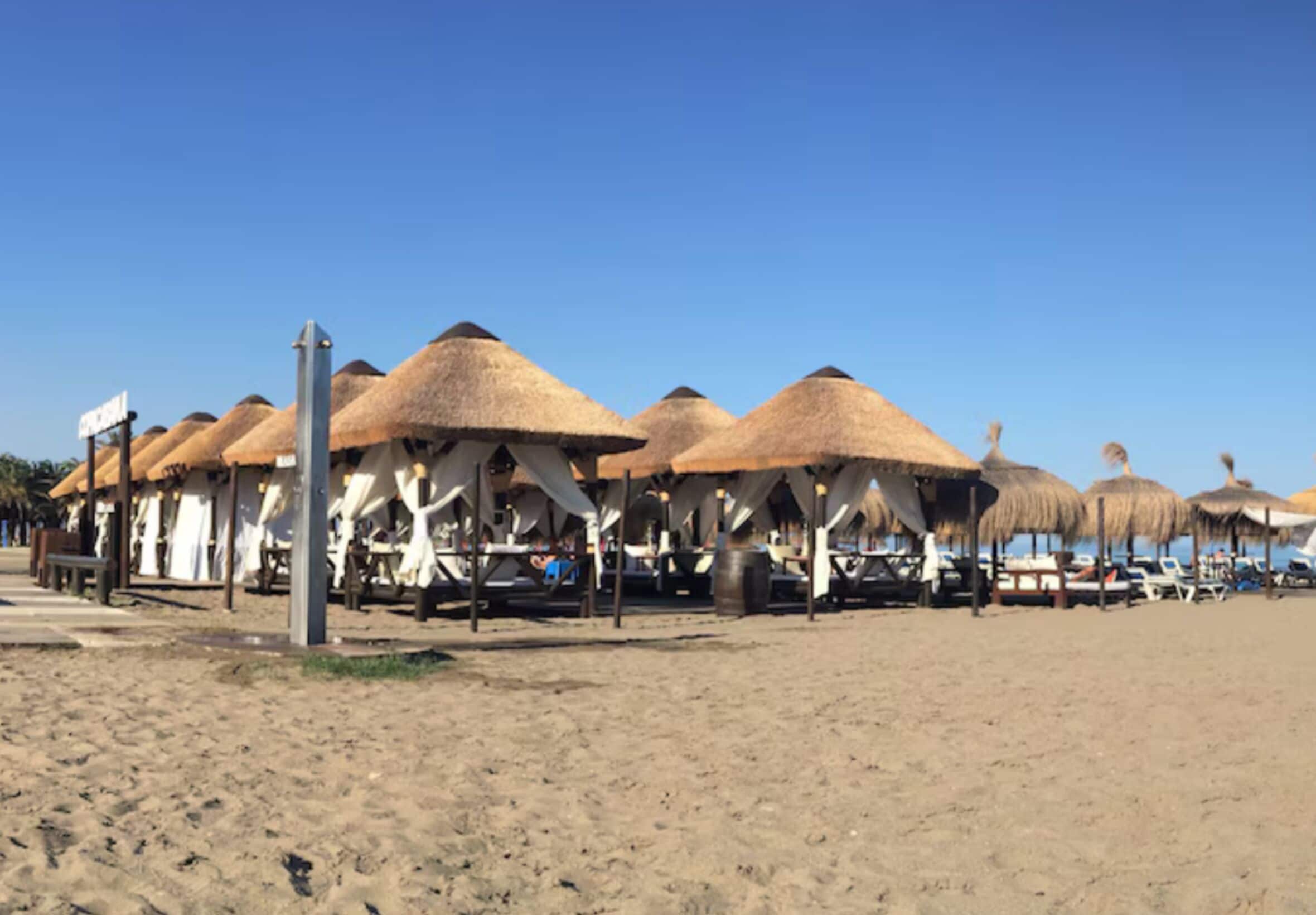 A beachside restaurant with thatched umbrellas and outdoor seating.
