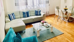 Ein modernes Wohnzimmer mit einer Eckcouch, einem Glastisch und einem Essbereich mit Stühlen und einem Tisch.