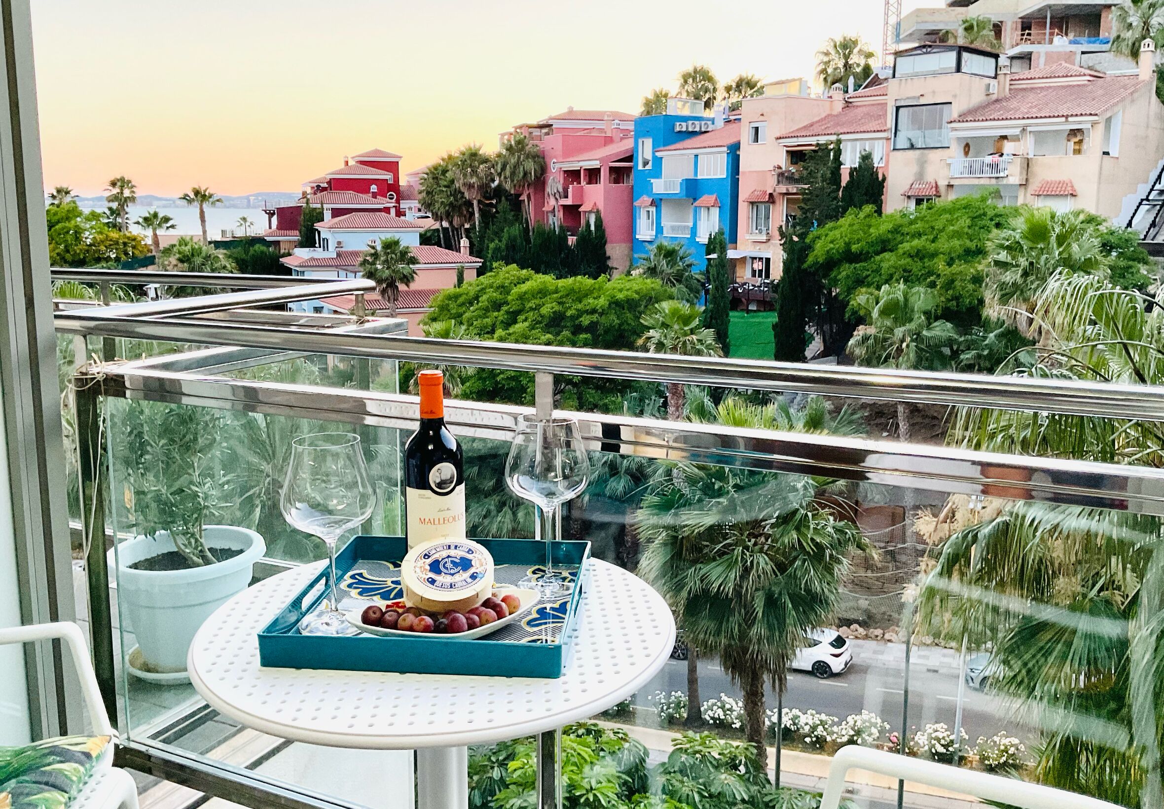 A balcony with a table set for a meal, a bottle of wine, and a glass.