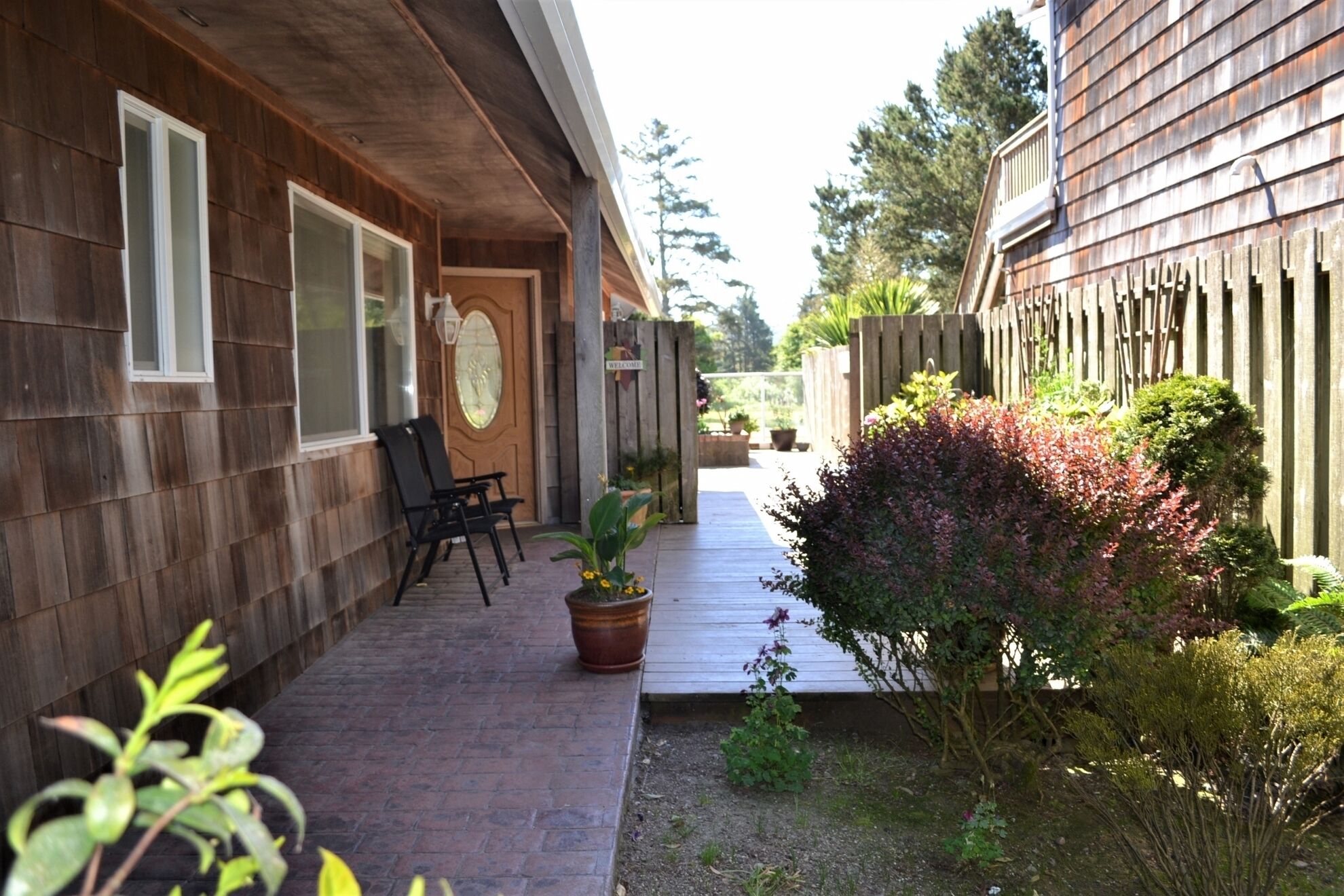 A wooden house with a covered patio, a welcome sign, and a wooden fence.