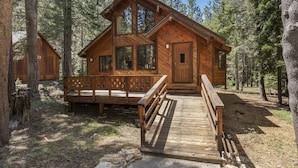 A wooden cabin with a deck and a covered entrance, surrounded by trees. - Creekside Cabin - Beautiful Dog Friendly Cabin in TD, Hiking and Biking Access (Truckee)