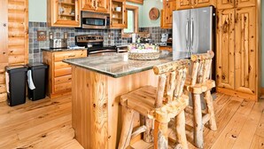 A log cabin kitchen with wooden cabinets, a central island, bar stools, and modern appliances.