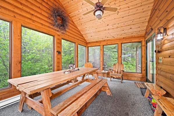 A wooden cabin with a large dining table, benches, and a ceiling fan. - Northwoods Luxury on Private Black Sand Beach (Two Harbors)