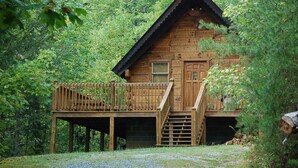 A wooden cabin with a balcony, a staircase, and a door. - Cozy Rustic Hot Tub Cabin w/Hike in River Access - SWB (Sevierville)