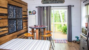 Een landelijke keuken met een houten tafel en stoelen, een bord boven de deur en uitzicht op het omliggende landschap.