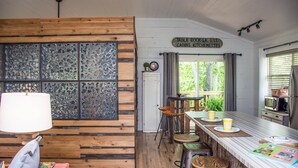 Een rustieke keuken met houten wanden, een eettafel met stoelen en een bord met de locatie erop.