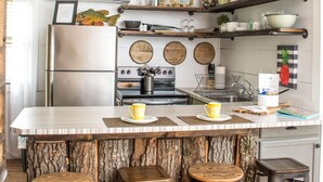 Een keuken met een centraal eiland, barstoelen, een koelkast en diverse keukenapparaten.