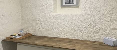 Una habitación pequeña con pared blanca con textura, una encimera de madera y un cuadro de un edificio.